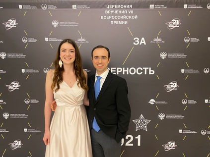 Loran Jacobs stands near an event branded backdrop stand inside the State Kremlin Palace.