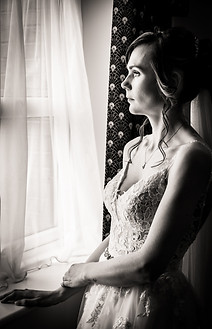 Mono image bride stood by window.