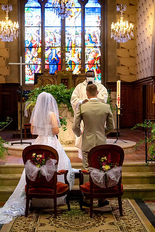 couple de marié se tenant debout devant le prêtre de l'église pour la cérémonie religieuse.