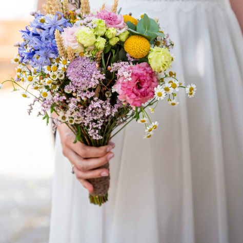 Bouqeut dans la main de la mariée. sa robe est floue en second plan