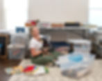 A lady sitting on the floor with her dog surrounded by boxes of scrapbooks, T-shirt quilts, and memories