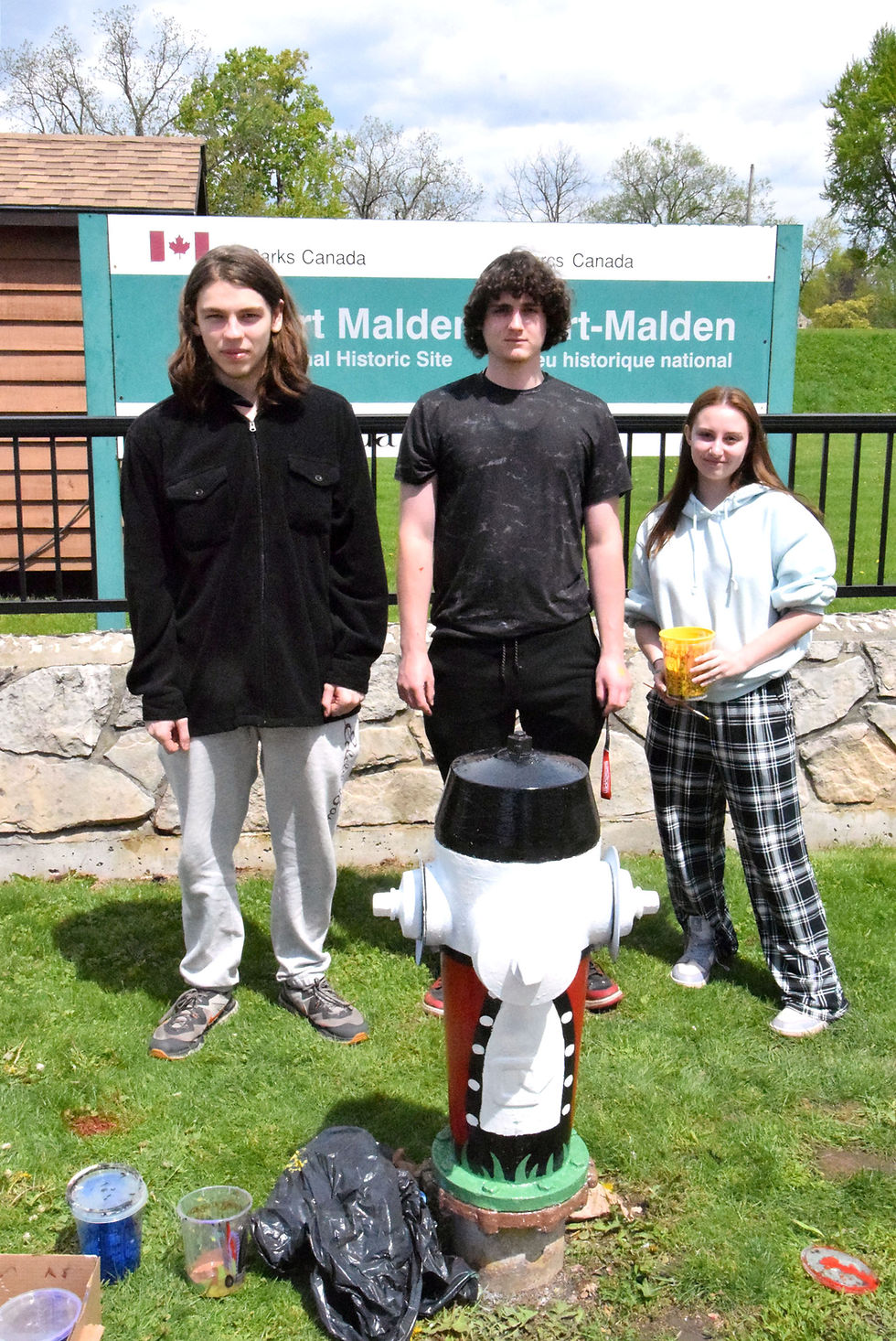 Connor Grondin, Landon Fallon and Alexis Thomas paint a hydrant in front of the Dalhousie St. entrance to Fort Malden National Historic Site.