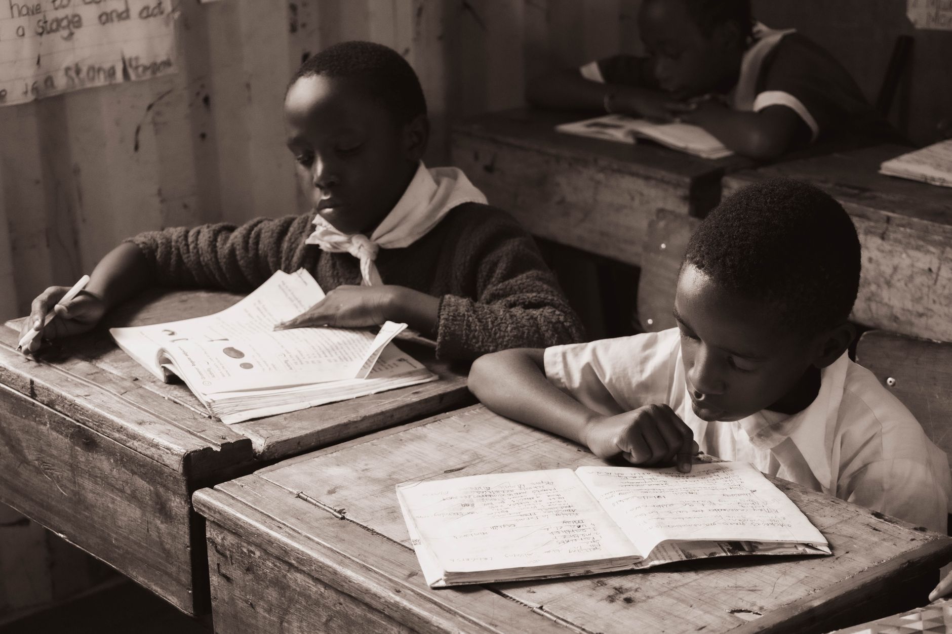 Student writing at a desk reviewing a paper draft