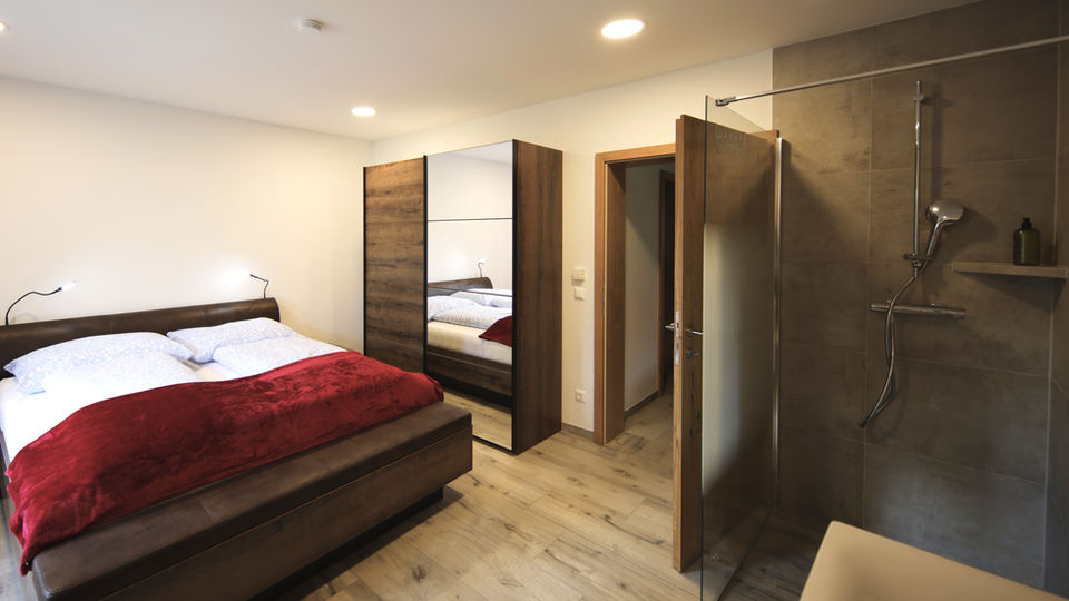 Modernes Schlafzimmer mit Doppelbett, Dusche und Kleiderschrank