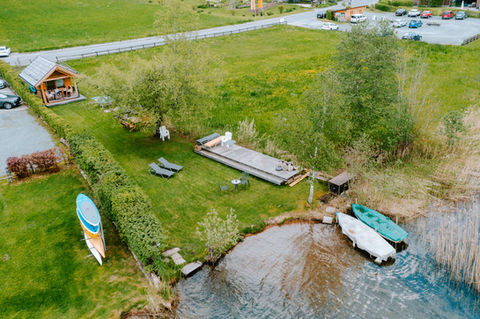 Ruhige Seenlandschaft mit Booten und Gartenmöbeln