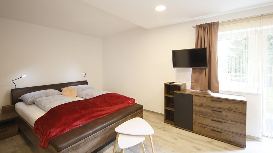 Modernes Schlafzimmer mit Doppelbett, TV und Kleiderschrank