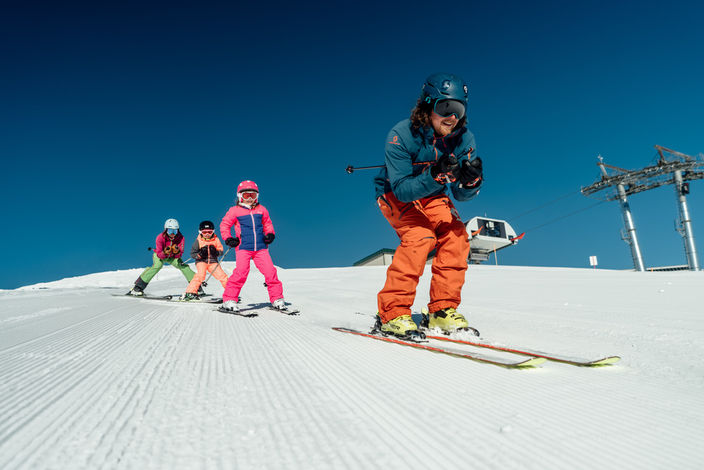 Skifahrer und Kinder auf der Piste