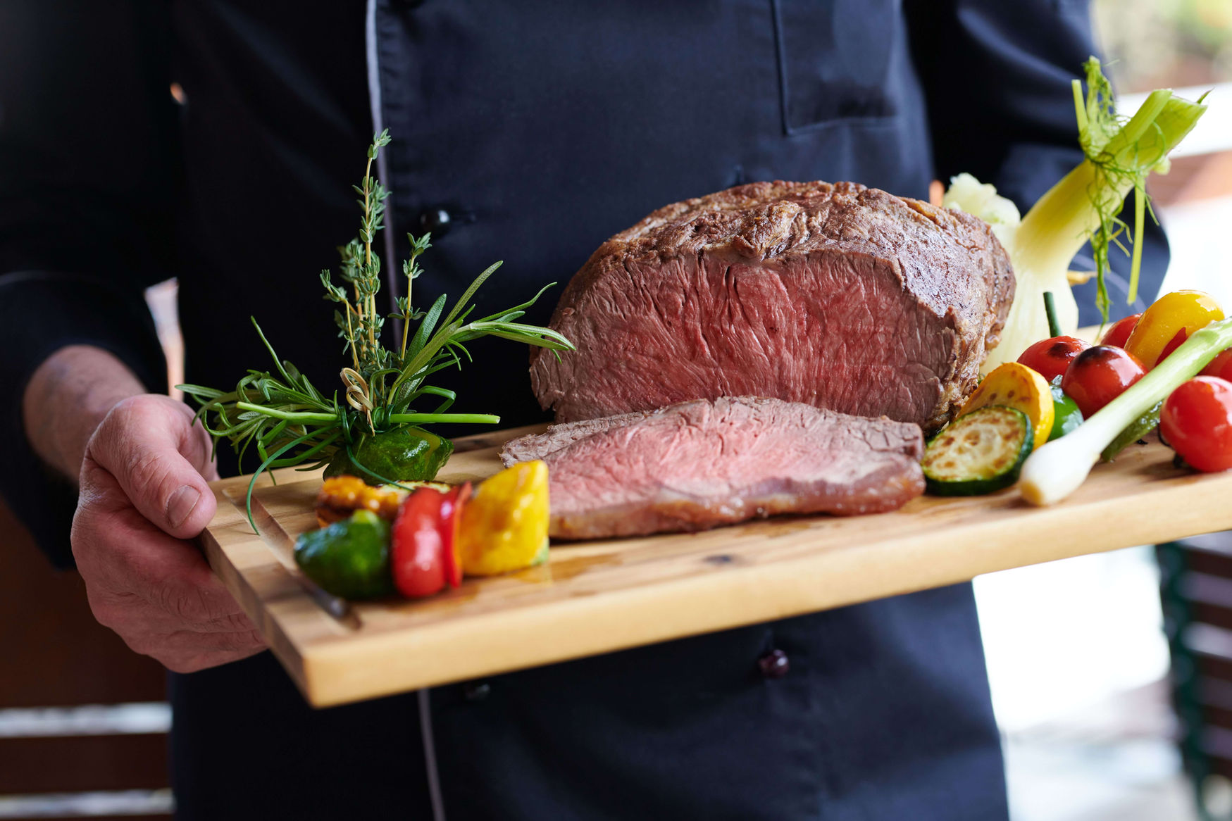Köchin präsentiert gebratenen Braten mit Gemüse