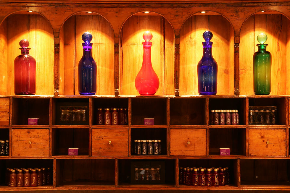 Close up image or a wooden display unit showing illuminated coloured bottles.