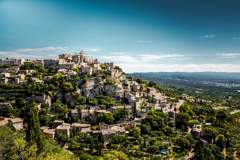 Scenic landscape of a historic stone village perched on a cliff overlooking the Luberon Valley countryside.