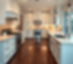 A large kitchen with white cabinets, light countertops, dark wood floors, stainless applia