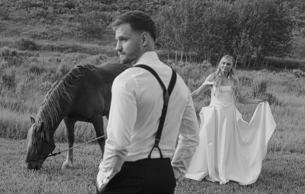 Bride and groom with horse in countryside setting.