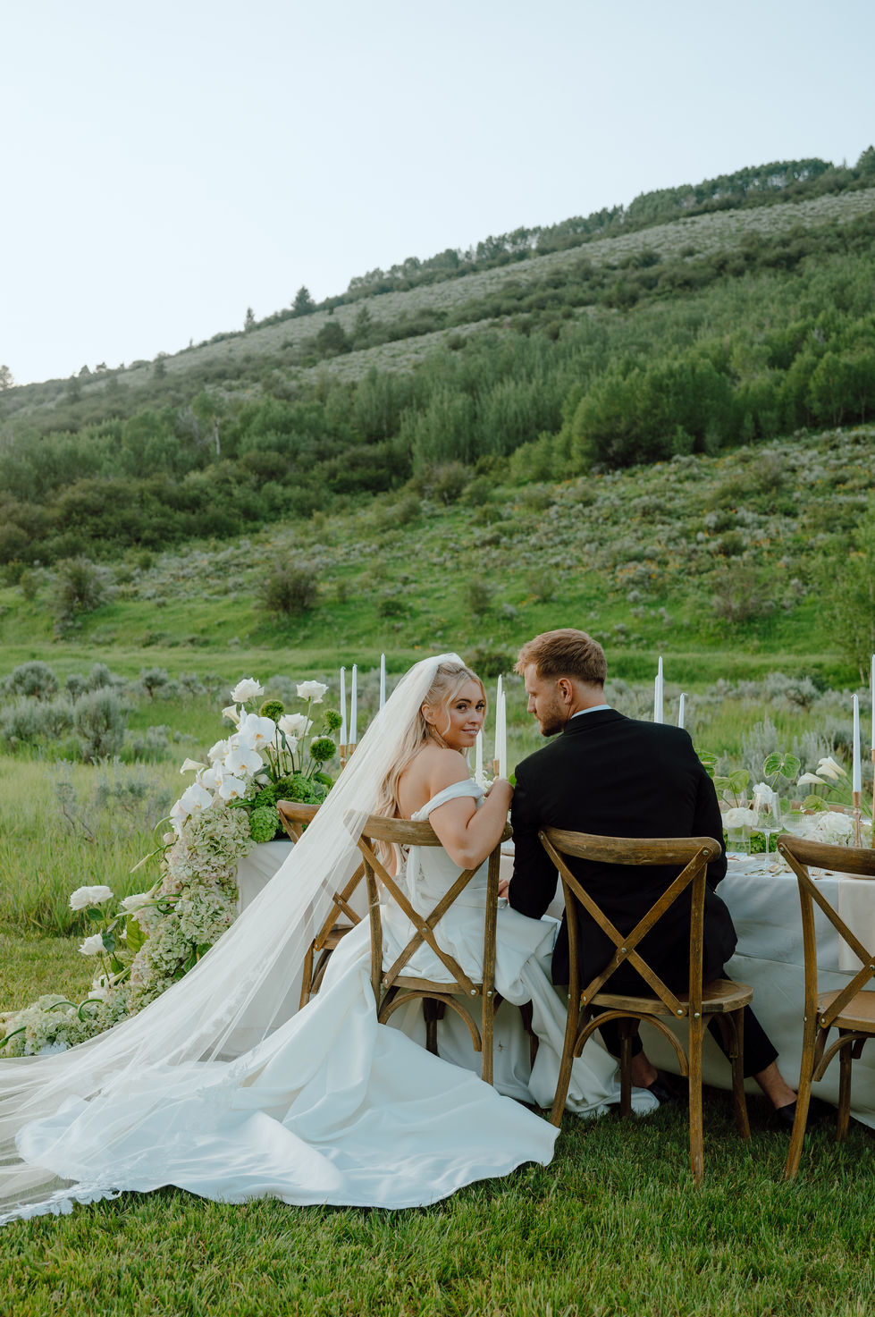 Bride and groom seated outdoors at wedding reception.