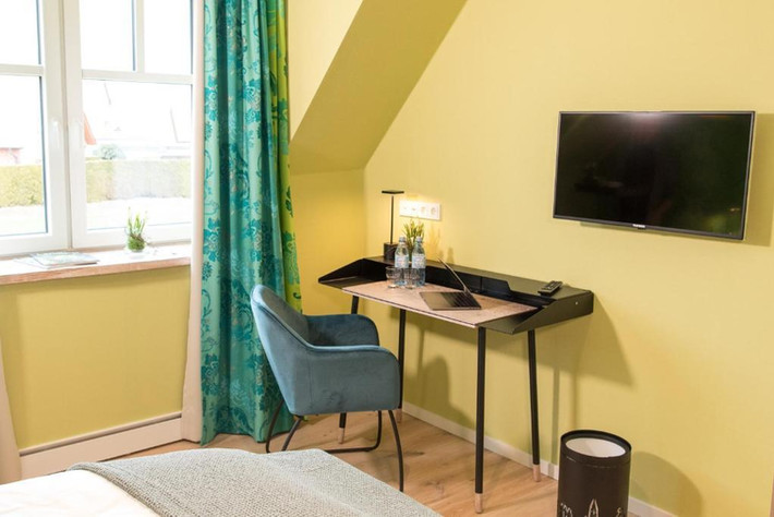 Hotelzimmer mit Schreibtisch, Stuhl und Fernseher