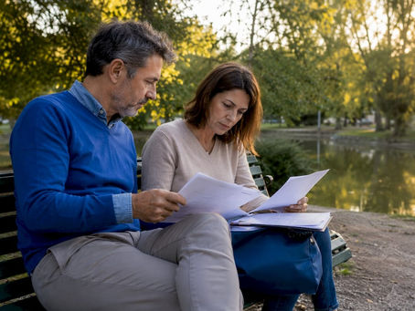 Una coppia seduta al tavolo che controlla le carte e i contratti per la vendita della propria casa.