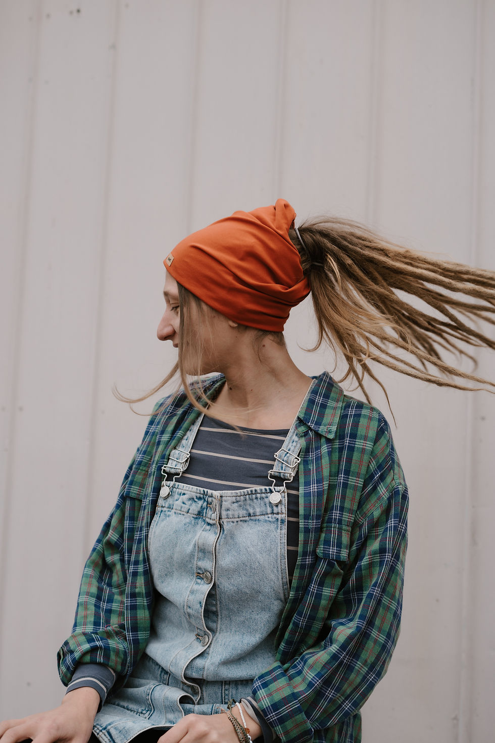 Miniaturbild: Frau mit langen Dread-Locks lässt ihre Haar schwungvoll zur Seite fliegen und trägt ein rotes Stirnband.