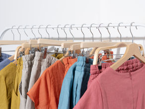 Leinenkleidung auf Holzkleiderbügeln auf Kleiderstange in bunten Farben