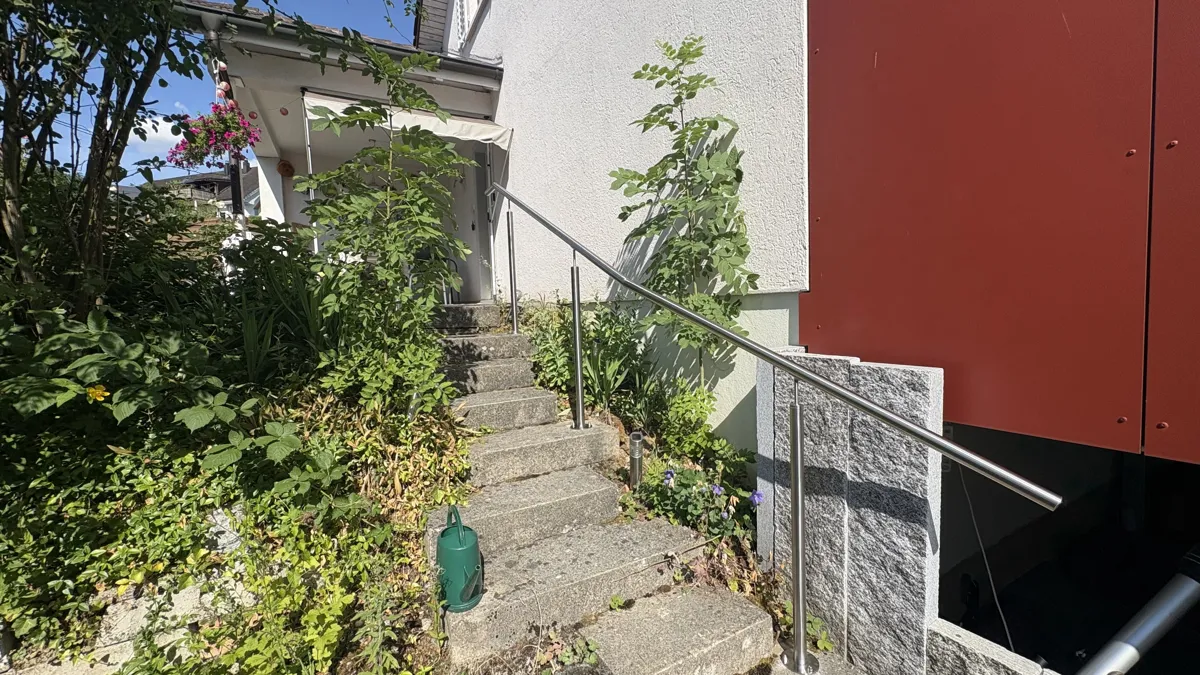 – Gesamtansicht der Gartentreppe mit abgewinkeltem Chromstahl-Handlauf und auf den Stufen montierten Pfosten.