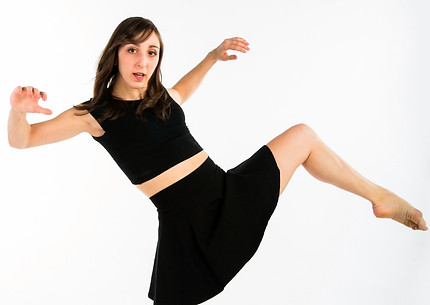 In all black against a white background, Melenie leans back while falling onto her left leg.