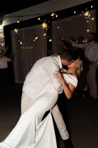 Couple kissing during wedding dance with sparklers, celebrating their special moment.