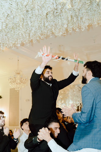 Man on shoulders celebrating with friends at a wedding. Wedding Photography Mohammed and Dana.
