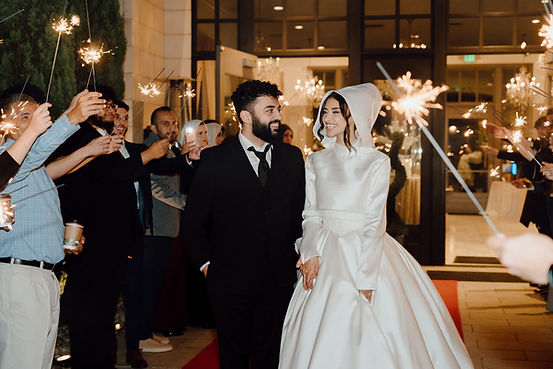 Couple walks through sparkler exit at wedding Photography, celebrating their marriage.