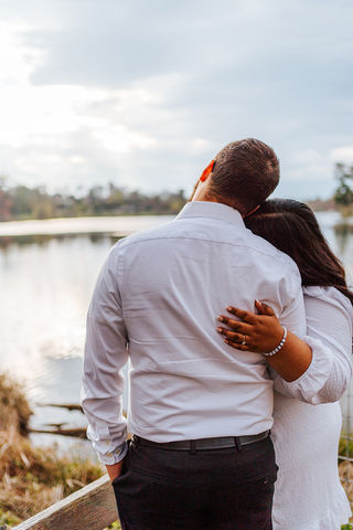 Couple embracing by a lake visible in the background, Engagement Photography Logan and Rocio.