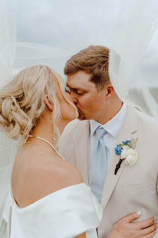 Bride and groom kissing under a veil, happy couple, joyful wedding day.