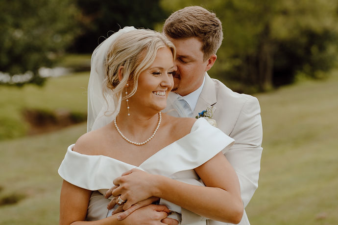 Bride and groom embrace on wedding day in an outdoor setting.
