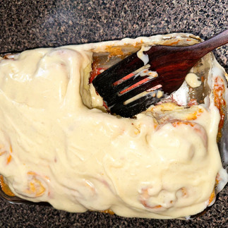 A picture of a pan of cinnamon rolls with vanilla bean cream cheese icing a spatula in the spot of 2 missing cinnamon rolls