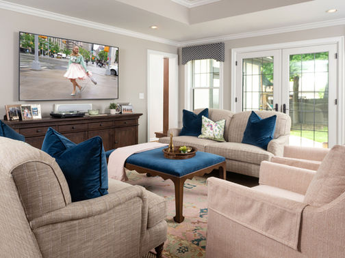 a beautiful family room with matching sofas and lounge chairs. the soft pink palette is pleasant