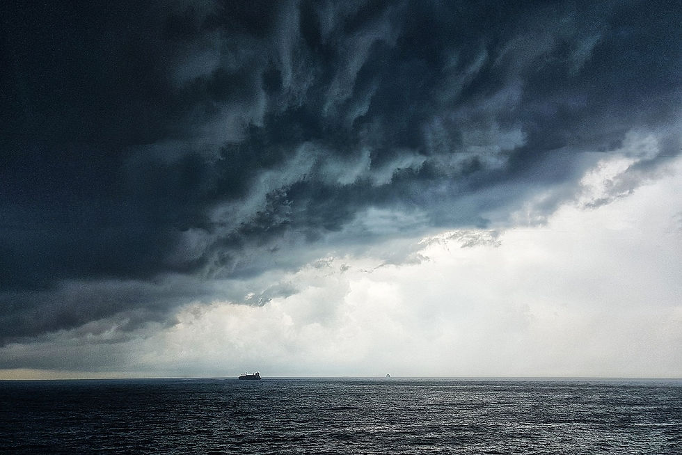 A photo of a small boat on the open sea with storm clouds rolling in above it.