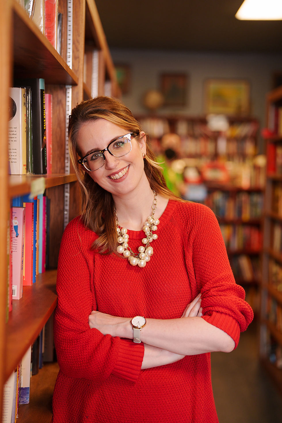 A photo of Rachel Wedeward in a library leaning against a bookshelf.