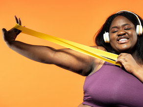 Femme noire souriante obèse tirant sur un élastique de gym jaune