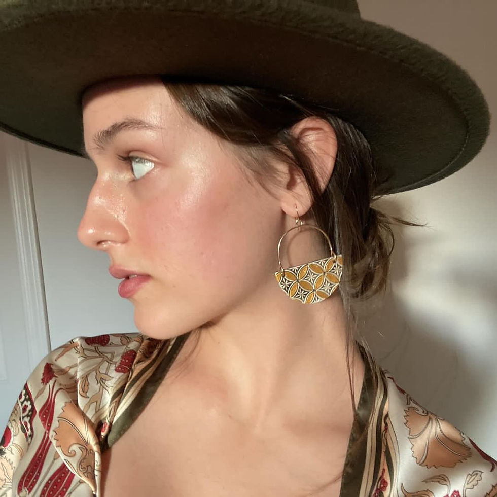 Model wearing a pair of luxury leather earrings gold and hand-stamped and painted
