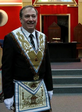 Homem sorrindo em uma roupa maçônica com Entre Dogmas e Mistérios, My Fraternity News.