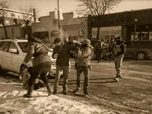 Intervenção policial num cenário urbano de inverno, com agentes armados e viaturas estacionadas.