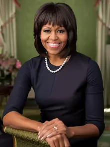 Retrato oficial de Michelle Obama na Sala Verde da Casa Branca, sentada e sorridente, com vestido azul-escuro e colar de pérolas — imagem serena e institucional.