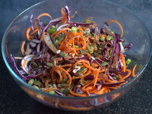 Bowl of crunchy Asian slaw with red cabbage, carrot, spring onions and mixed seeds.