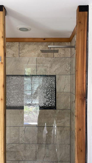 Custom glass walk-in shower with porcelain tile walls and pebble floor completed by RiverRock Renovation in Wynnewood PA.
