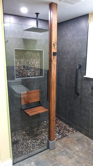 Curbless walk-in shower with rainfall showerhead, pebble floor, and teak bench in Eagleville PA