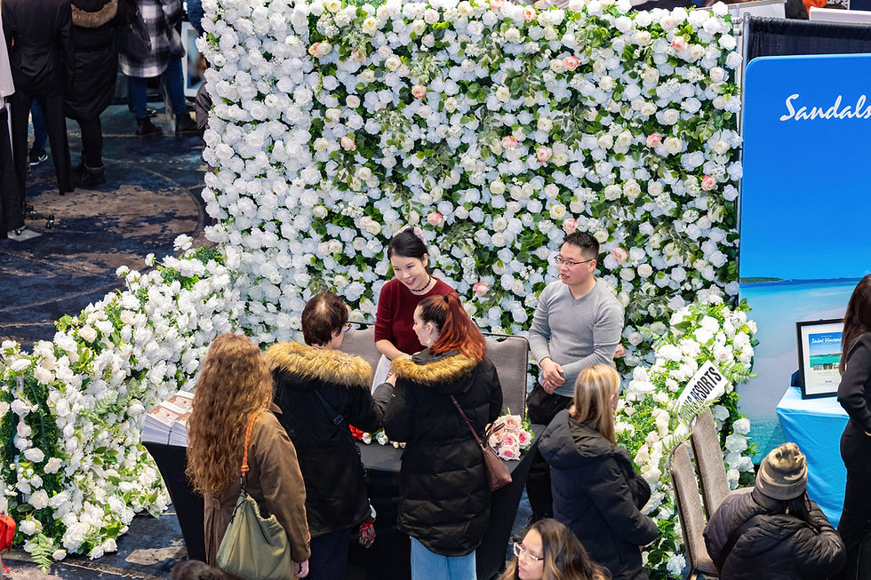 People mingle near a beautiful flower wall at a wedding show, exploring floral arrangements and event ideas together.