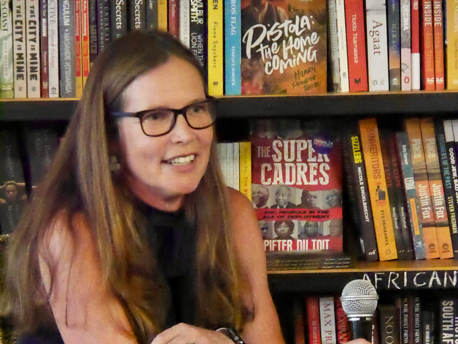 White woman holding a microphone in a book shop
