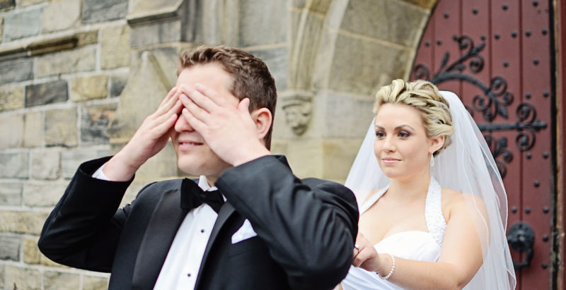 The bride and groom stand happily together outside a church, capturing their first look on their wedding day.