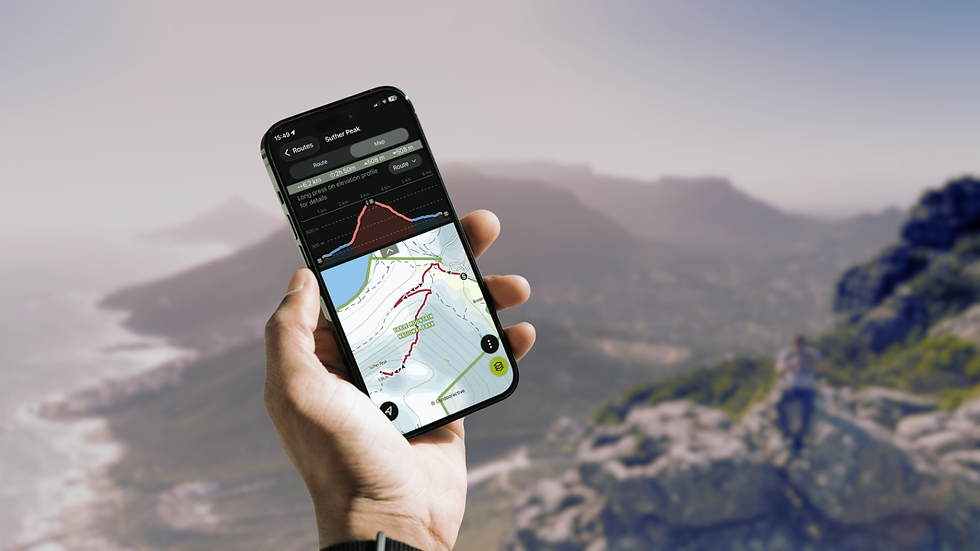 Hand holding a phone with a hiking map app open, overlooking mountains and coastline. A hiker with a dog is visible on a rocky cliff.
