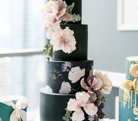 A black wedding cake adorned with flowers.