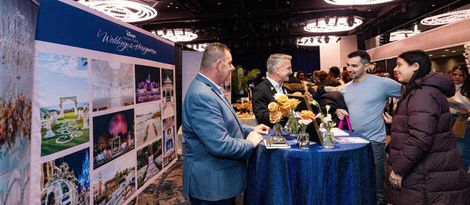 Attendees gather around a blue tablecloth-covered table at a Disney wedding exhibitor showcase.