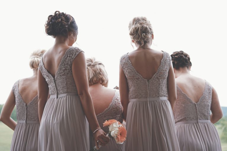 Bridesmaids in elegant grey dresses stand together, smiling and celebrating a special moment.