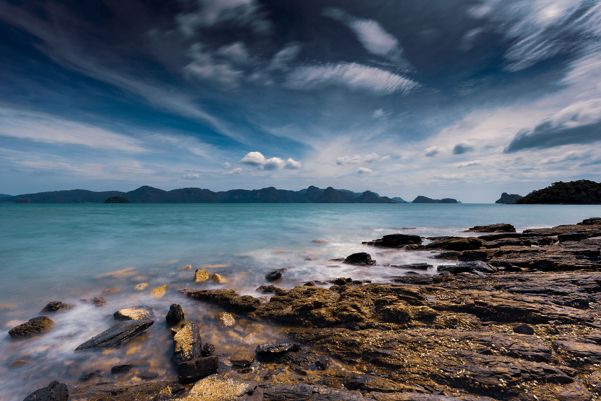Scenic coastal view: tranquil ocean, rocky shore, dramatic sky