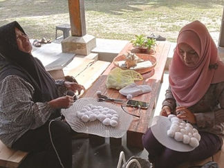Two women crafting white textile items